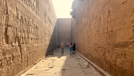 Tourists-walking-and-talking-while-exploring-hieroglyphs-in-Horus-Temple-at-Edfu