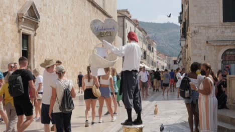 Man-selling-souvenirs-in-historical-streets-of-Dubrovnik,-handheld-view