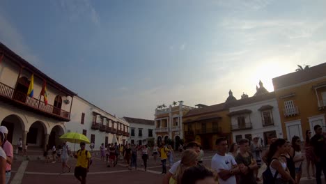 Ein-Reiseleiter-Mit-Einem-Gelben-Regenschirm-Geht-In-Der-Nähe-Einer-Gruppe-Von-Touristen-Entlang,-Die-Mitten-Auf-Einem-Platz-In-Der-Altstadt-Von-Cartagena-De-Indias,-Kolumbien,-Stehen