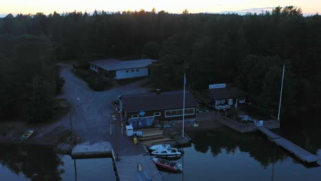Aerial-view-of-a-traditional-midsummer-pole,-at-a-harbor,-in-the-archipelago-of-Uusimaa,-Finland---tilt-up,-drone-shot