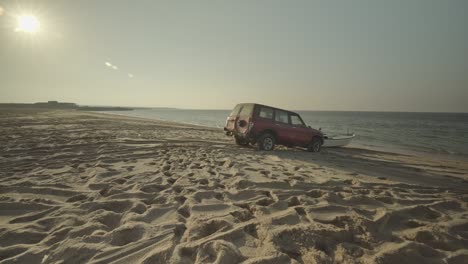 Roter-Geländewagen-Schiebt-Boot-über-Den-Sandstrand-Zum-Meer-Im-Oman