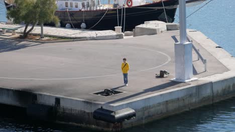 Boy-with-yellow-hoodie-stand-on-the-harbor-and-wait