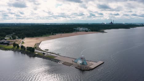 Aerial-drone-view-over-the-Nallikari-lighthouse-and-beach,-towards-the-Eden-spa,-in-Oulu,-Finland