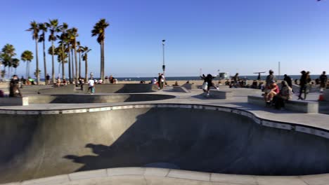 People-skating-at-the-Venice-Beach-Skate-Park,-on-a-sunny-day,-in-Los-Angeles,-California,-USA---Pan-shot
