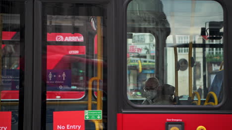 Public-transport-in-London-during-Coronavirus-Covid-19-lockdown-with-man-on-red-London-bus-wearing-face-mask-covering-when-public-transport-was-quiet-and-deserted-with-no-people-in-England,-Europe