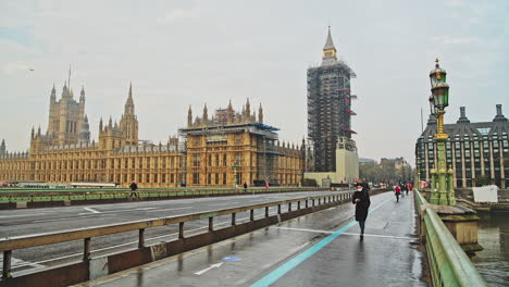 London-in-Coronavirus-Covid-19-lockdown-with-empty-roads-and-streets-with-no-cars-or-traffic-at-Westminster-Bridge-with-Houses-of-Parliament,-Big-Ben-and-people-walking-in-England,-UK-at-rush-hour
