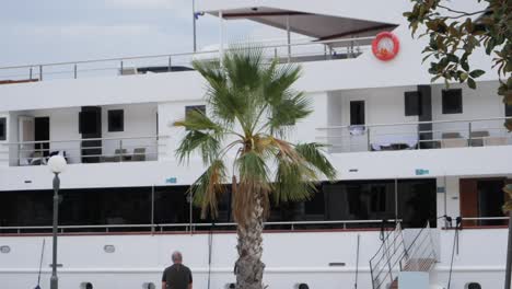 Person-sitting-and-admiring-massive-luxury-yacht-in-Croatia,-Slano-town