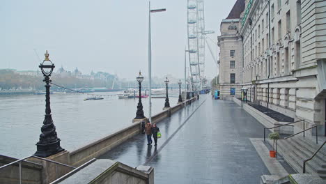 Quiet-and-empty-Central-London-at-the-London-Eye-during-Covid-19-Coronavirus-pandemic-lockdown,-with-two-people-walking-for-daily-exercise-in-the-city,-London,-England,-Europe