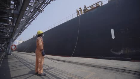 Hafenarbeiter-Bei-Der-Arbeit,-Der-Ein-Großes-Frachtschiff-Im-Hafen-Festmacht