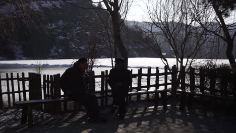 Gubei-Water-Town-2-men-sitting-by-frozen-lake