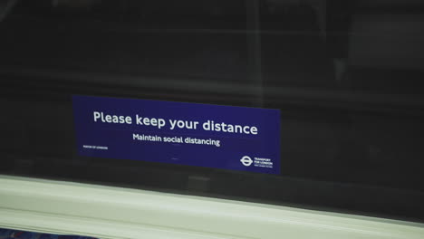 Covid-19-Coronavirus-information-sign-in-London-Underground-tube-train-carriage-for-social-distancing-on-public-transport-in-England,-UK