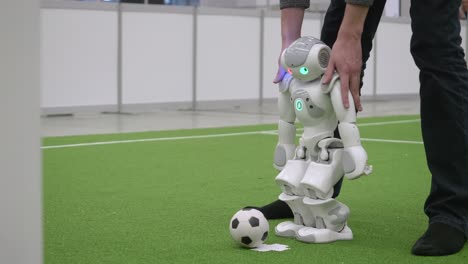 Engineer-Holding-Shoulders-Of-Nao-Robot-As-It-Walks-To-Kick-Ball