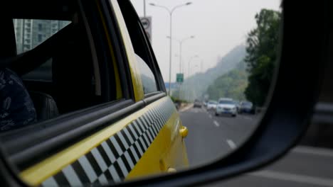 Vista-Del-Espejo-De-Ala-De-Taxi-Amarillo-Reflejo-Del-Tráfico-Por-Carretera-En-Beijing,-China