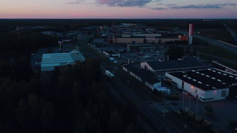 Aerial-view-following-trucks-at-a-industrial-area-in-Vaasa,-dusk-in-Finland---reverse,-drone-shot
