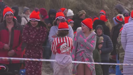 Group-of-shivering-children-waiting-in-line-at-Texel-beach,-ready-to-dive-in-New-Year's-Plunge-,-in-North-Holland,-Netherlands---Medium-static-shot