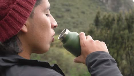 Guy-taking-a-sip-to-hydrate-during-a-break-on-a-hiking-trip-through-the-mountains-of-Peru,-Huaraz,-Yungay