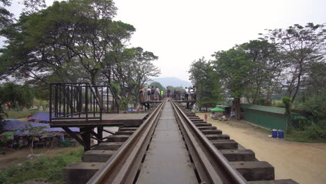 Hyperlapse-Timelapse-of-Walking-on-Railway-Toward-River-Kwai-Bridge,-Popular-Tourist-Attraction-in-Thailand