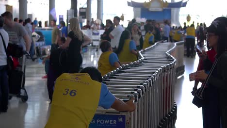 The-airport-workers-collect-the-trolleys-with-the-crowd-of-people-in-background