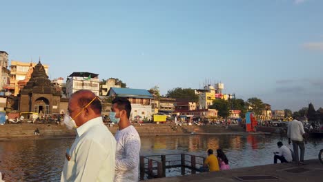 Tagesszene-Im-Ramkund-Viertel-In-Nashik,-Indien-Mit-Gläubigen,-Die-Im-Fluss-Godavari-Baden,-Und-Dem-Tempel-Shree-Ganga-Godavari-Am-Ufer