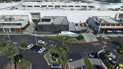 Aerial-Drone-flying-close-across-Del-Amo-Fashion-Center-parking-lot-and-shops-with-one-under-construction