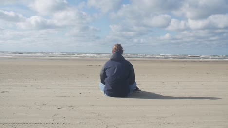 Junger-Mann-Sitzt-Am-Strand-Und-Meditiert