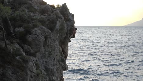 Strong-person-climbing-steep-seaside-cliff-without-safety-equipment,-Croatia,-Brela