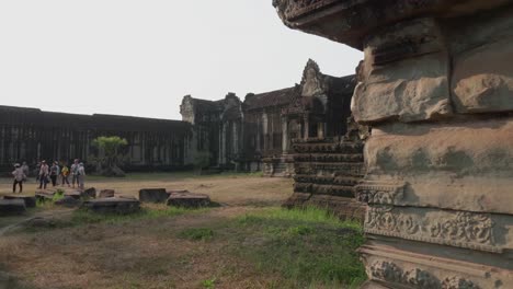 Sie-Enthüllt-Einen-Eingang-Im-Innenhof-Des-Angkor-Wat-Tempels,-Während-Eine-Touristengruppe-Ein-Anderes-Gebäude-Betrachtet