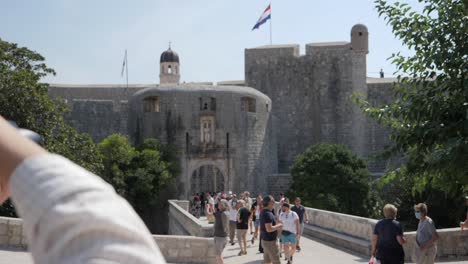 Woman-photographer-taking-picture-of-Dubrovnik-castle-with-waving-flag,-motion-view