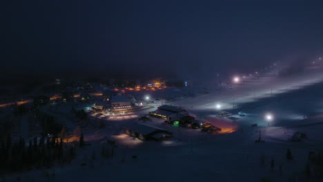 Aerial-view-around-the-Yllasjarvi-ski-resort,-foggy,-winter-evening,-in-Yllas,-Lapland---orbit,-drone-shot