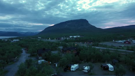 Luftaufnahme-Des-Dorfes-Kilpisjarvi-Und-Des-Saanatunturi-Felsens,-Mitternachtssonne,-In-Lappland,-Finnland---Aufgehender-Drohnenschuss