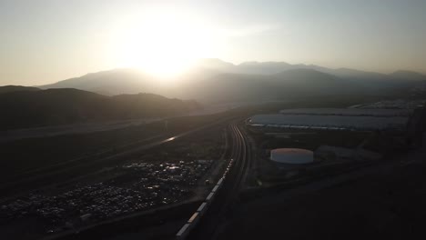 Luftaufnahme-Des-Sonnenuntergangs-über-Dem-Sandigen-Bernandino-Tal-Und-Dem-BNSF-Güterzug-Auf-Der-Eisenbahn,-Kalifornien,-USA
