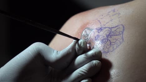 Close-Up-Slow-Motion-of-Tattoo-Machine-in-Hand-of-Artist-Drawing-Elephant-on-Skin-of-Young-Female