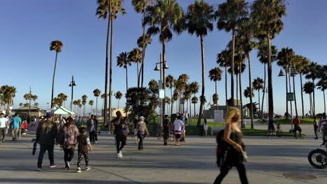 Masked-people-walking-around-the-Venice-Boardwalk,-in-the-afternoon,-in-Los-Angeles,-California,-USA---Quiet-do-to-the-Coronavirus-pandemic---Handheld-static-shot
