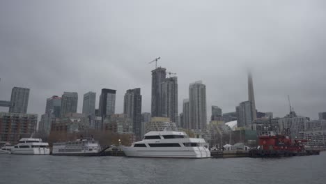Bewölkter-Tag-über-Der-Uferpromenade-Von-Toronto-Mit-Festgemachten-Booten-Und-Dem-CN-Tower,-Der-Teilweise-Im-Nebel-Sichtbar-Ist