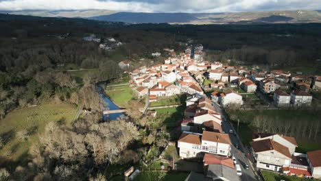 Aerial-pullback-along-river-above-quaint-Spanish-village-in-countryside