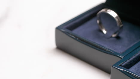 A-close-up-of-a-couple's-engagement-rings-that-is-placed-on-a-dark-blue,-velvet-covered-box