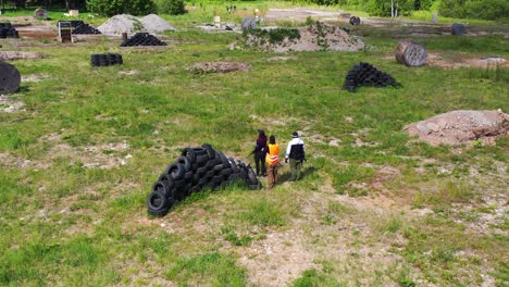 Airsoft-players-near-tire-pile-cover,-ready-for-game-start-and-attack