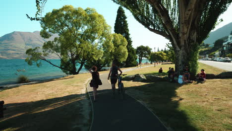 People-Walking-And-Relaxing-By-The-Shore-Of-Lake-Wakatipu-In-Queenstown,-New-Zealand