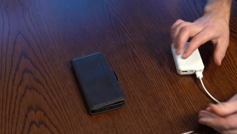 White-Powerbank-Connected-to-Phone-on-Wooden-Table