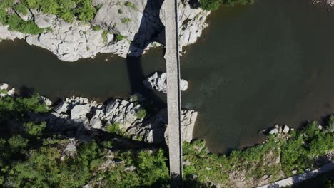 Overhead-drone-shot-of-the-length-of-the-Devil's-Bridge-and-Arda-River-located-in-the-town-of-Ardino-near-the-Rhodope-Mountains-in-Bulgaria