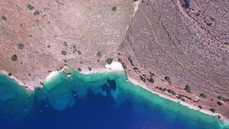Overhead-retreating-drone-shot-of-Agriosiko,-an-isolated-beach-off-the-coast-of-the-island-of-Kefalonia,-Greece