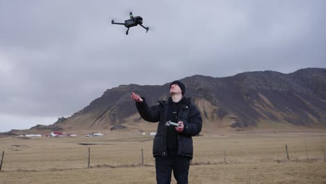 Drone-hover-in-air-and-land-in-man-hand,-Icelandic-mountain-background
