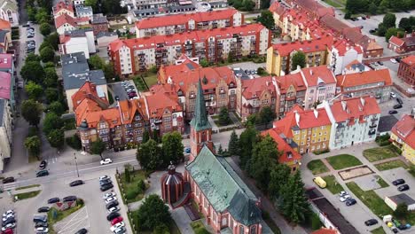Church-tower-and-red-rooftops-of-Elk-city-in-Poland,-aerial-orbit-view