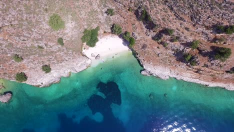Overhead-retreating-drone-shot-of-the-coastline-of-Agriosiko-Beach-a-secret-getaway-in-Kefalonia,-situated-in-the-Ionian-islands-off-the-coast-of-Greece
