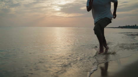 young-Male-running-on-the-beach-in-the-water-at-sunrise-super-slow-motion