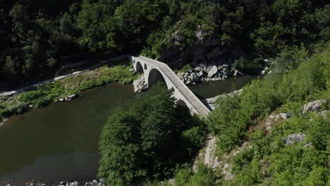 Approaching-drone-shot-with-a-view-from-above-of-the-Devil's-Bridge-and-Arda-River-located-near-the-town-of-Ardino-at-the-foot-of-the-Rhodope-Mountains-in-Bulgaria