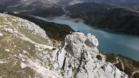 Toma-Panorámica-De-Drones-De-Personas-Caminando-Por-El-Embalse-De-Bovilla-Con-El-Lago-Bovilla-Al-Fondo,-Albania,-Europa