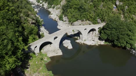 Drone-panning-from-the-left-to-the-right-side-of-the-frame-above-the-Devil's-Bridge-in-the-town-of-Ardino-near-the-Rhodope-Mountains-in-Bulgaria