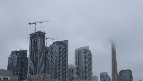 Nebel-Hüllt-Den-CN-Tower-Inmitten-Der-Aufsteigenden-Wolkenkratzer-Und-Baukräne-In-Toronto-Ein,-Die-Herauszoomen