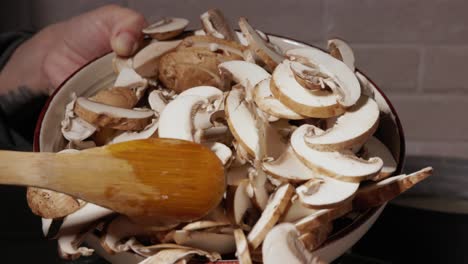 Pilze-Kochen-–-Pilzscheiben-Mit-Einem-Holzlöffel-In-Die-Pfanne-Gießen